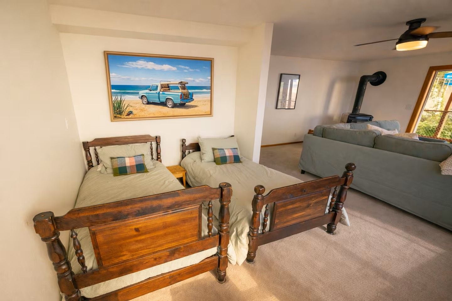 Un dormitorio con una cama doble, un sofá, un ventilador de techo y un cuadro con una playa.