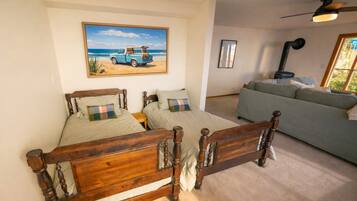 Un dormitorio con una cama doble, un sofá, un ventilador de techo y un cuadro con una playa.