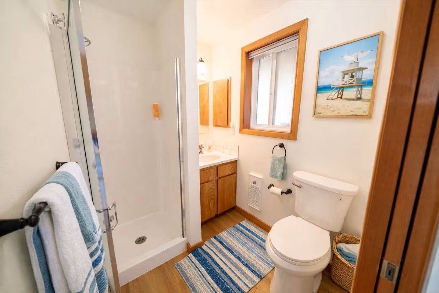 Ein Badezimmer mit Dusche, Toilette, Waschbecken und einem Fenster mit Blick auf den Strand.