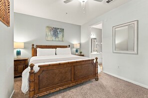 A bedroom with a wooden bed, two bedside tables, a ceiling fan, a painting, and a large mirror. - Work, Play and Stay, 3BR, Prime Orlando Location (Orlando)