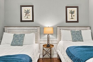 A hotel room with two beds, a nightstand with a lamp, and two framed botanical prints on the wall. - Work, Play and Stay, 3BR, Prime Orlando Location (Orlando)