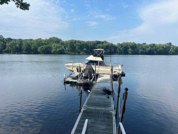 Un bateau était amarré à un quai, avec un lac paisible et une rive boisée en arrière-plan.