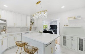 A modern kitchen with white cabinetry, a central island, and gold accents.