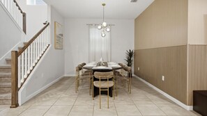 A dining area with a round table, chairs, and a chandelier. - 7BR Villa Solara Resort Pool & Cinema Near Disney (Kissimmee)