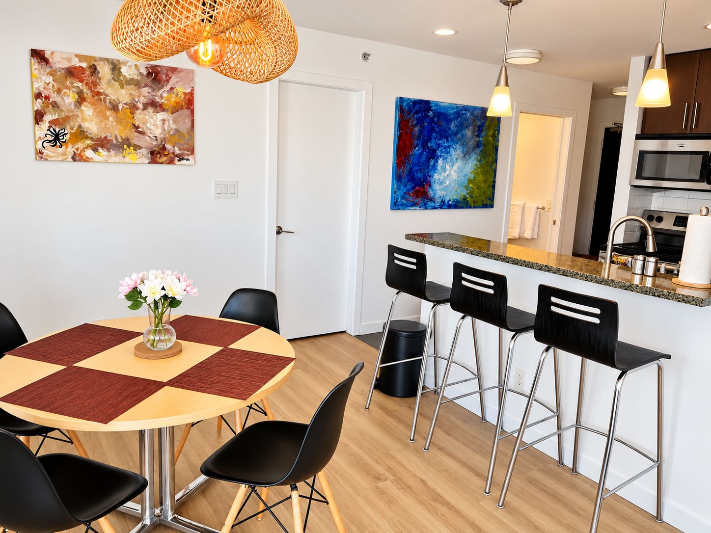 A modern kitchen with a microwave, stove, and bar stools.