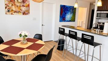 A modern kitchen with a microwave, stove, and bar stools.