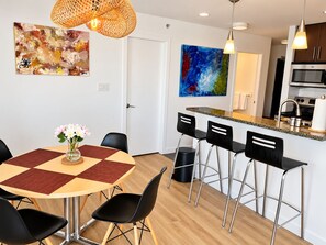 A modern kitchen with a microwave, stove, and bar stools. - 2BR+Sofabed, 2Bath, Private 500sqft sundeck, EV Parking w/Pool, Sauna, Hot Tub (Vancouver)