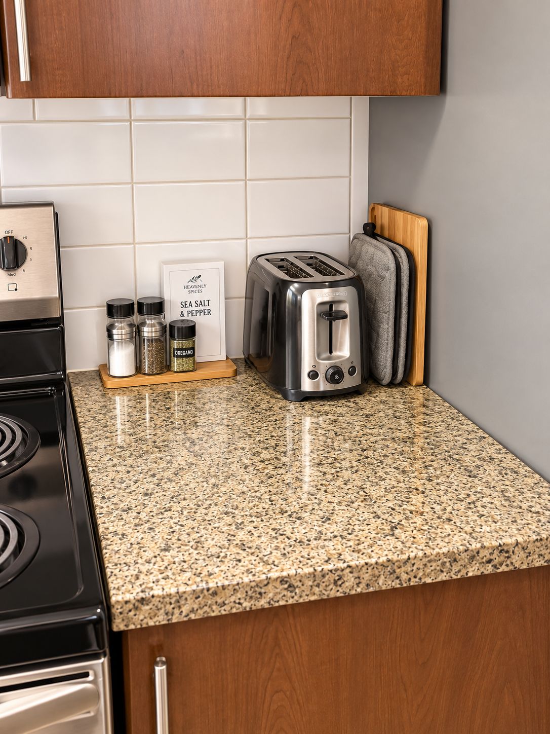 A kitchen with a granite countertop, a toaster, a stove, and a spice rack.