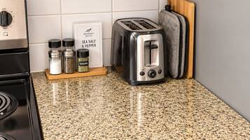 A kitchen with a granite countertop, a toaster, a stove, and a spice rack.