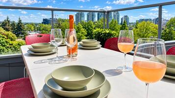 A table set for dining with a bottle of wine, glasses, and bowls, overlooking a cityscape.
