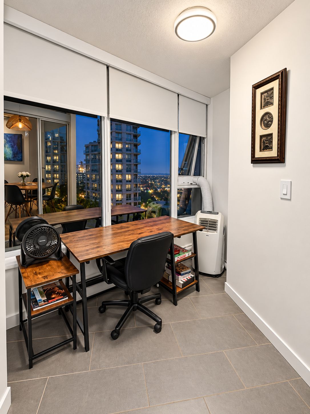 A modern office space with a wooden desk, black office chair, and a standing fan.