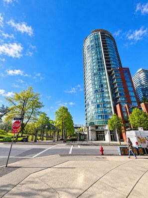 A modern building with a curved facade, a stop sign, and a pedestrian crossing. - 2BR+Sofabed, 2Bath, Private 500sqft sundeck, EV Parking w/Pool, Sauna, Hot Tub (Vancouver)