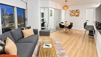 A modern living room with a sofa, coffee table, and dining area with chairs.