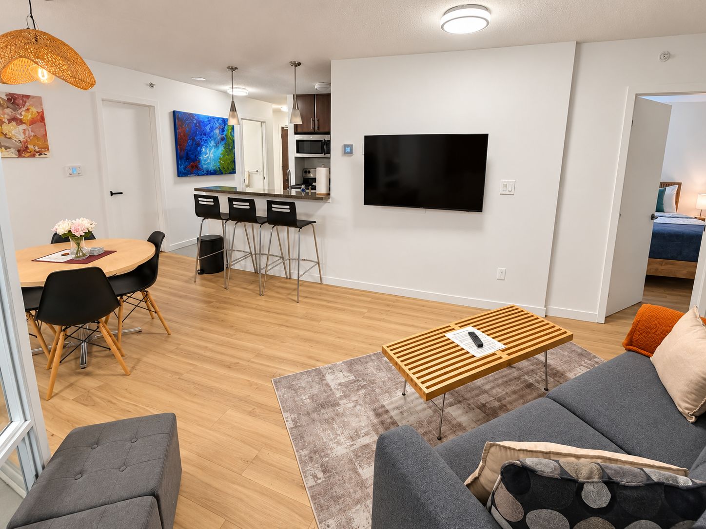 A modern living room with a sofa, a coffee table, and a dining area with chairs and a table.
