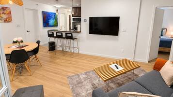 A modern living room with a sofa, a coffee table, and a dining area with chairs and a table.