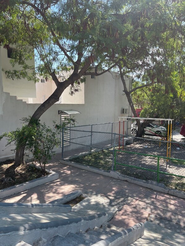 A paved pathway leading to a gated area with a playground.