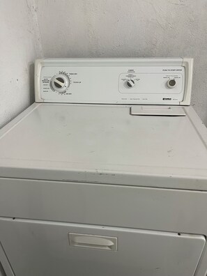 Une machine à laver blanche, à chargement frontal, dotée d’une seule porte et de boutons de commande pour régler la température et la vitesse d’essorage.