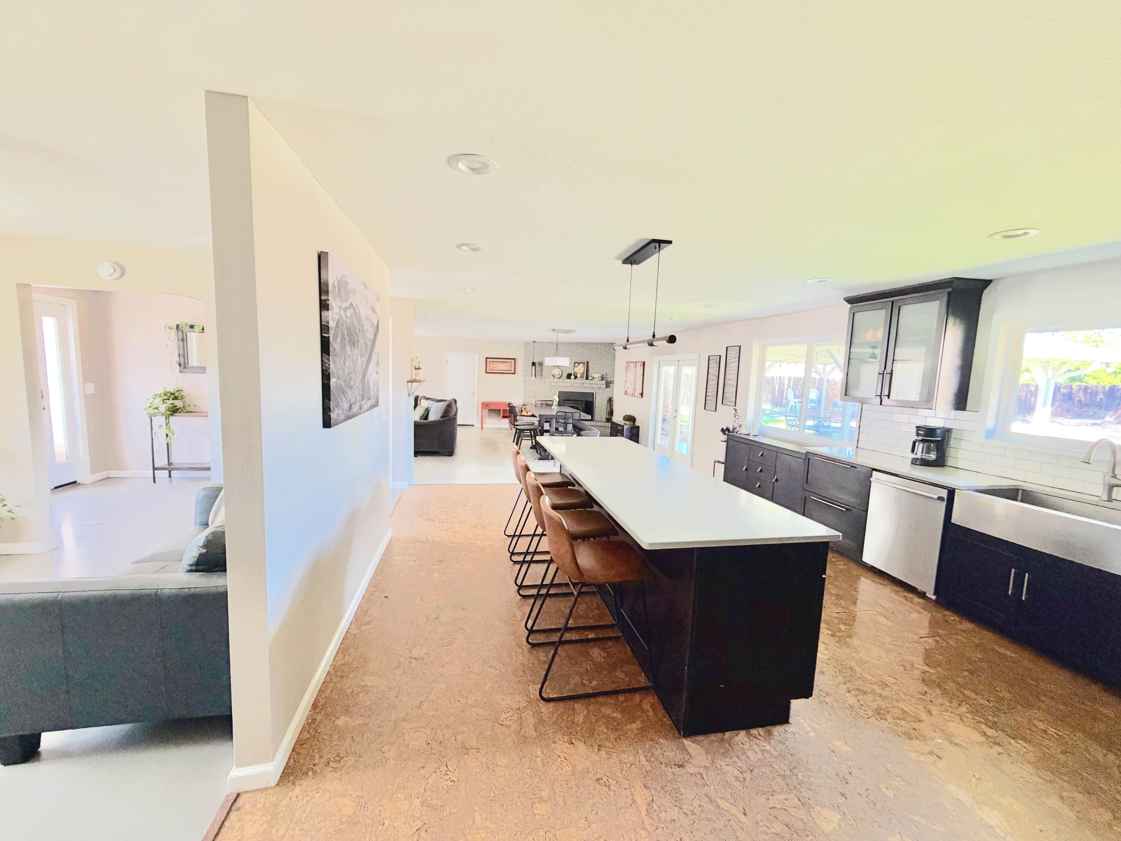 Une cuisine moderne dotée d’un grand îlot central, de meubles de couleur sombre et d’une grande fenêtre.