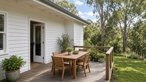 A wooden deck with a table and chairs, surrounded by potted plants and a house with white siding. - Peaceful Luxury Pad (Ascot Vale)