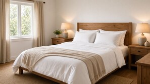 A neatly made bed with a wooden headboard, two bedside tables with lamps, and a window with curtains. - Peaceful Luxury Pad (Ascot Vale)