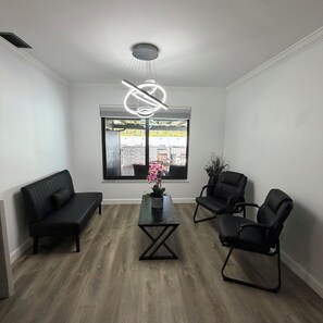 A modern room with a black sofa, a black armchair, and a coffee table with a vase of flowers. - Casa Sol: Jacuzzi, Outdoor Kitchen & BBQ in Deerfield Beach (Deerfield Beach)
