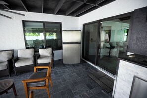 A covered patio area with wicker furniture, a refrigerator, and a glass door leading to an indoor space. - Casa Sol: Jacuzzi, Outdoor Kitchen & BBQ in Deerfield Beach (Deerfield Beach)