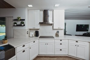 A modern kitchen with white cabinetry, a built-in stove, and a large window. - Casa Sol: Jacuzzi, Outdoor Kitchen & BBQ in Deerfield Beach (Deerfield Beach)