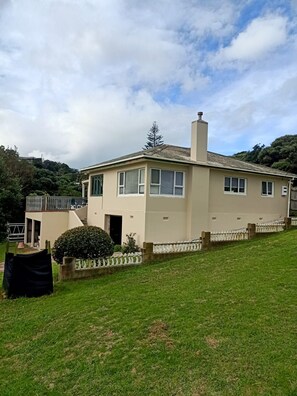 A two-story house with a balcony, a chimney, and a well-maintained lawn.