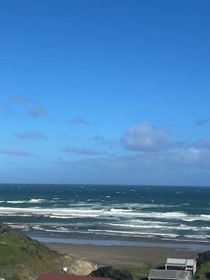 A coastal landscape with a view of the ocean, waves, and a beach.