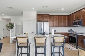 Una cocina moderna con una isla central, electrodomésticos de acero inoxidable y armarios de madera.