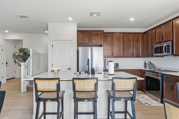A modern kitchen with a central island, stainless steel appliances, and wooden cabinets.