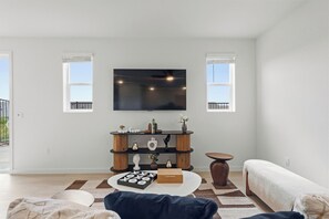 Una sala moderna con una televisión de pantalla plana, un mueble bajo de madera escalonado y una alfombra estampada.