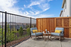 Une terrasse extérieure avec deux fauteuils à bascule, une petite table et une clôture en bois.