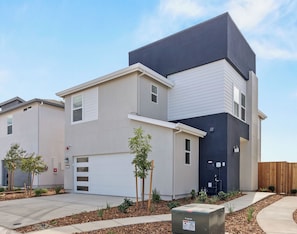 A modern multi-story residential building with a garage, a small front yard with young trees, and a utility box. - Sunset Haven Rocklin.
Brand-New Home with Stunning Sunset Views (Rocklin)