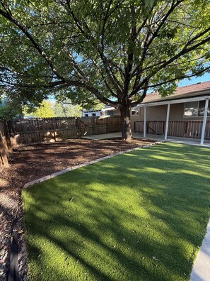 A backyard with a tree, a wooden fence, and a lawn. - Perfect 2-bedroom apartment in welcoming Loveland for your stay (Loveland)