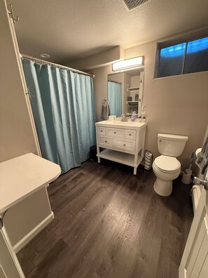 Un bagno con un mobile lavabo bianco, un WC, una tenda blu per la doccia e uno specchio sopra il lavandino.