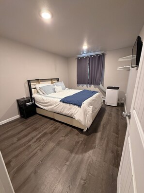 A bedroom with a bed, a nightstand, a heater, and a window with curtains. - Perfect 2-bedroom apartment in welcoming Loveland for your stay (Loveland)