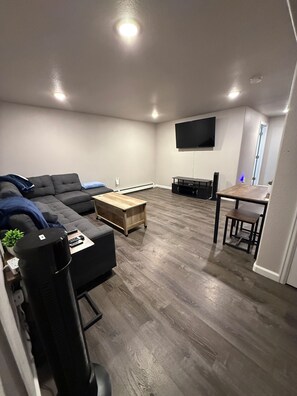 A living room with a sectional sofa, a coffee table, a TV mounted on the wall, and a dining table with chairs. - Perfect 2-bedroom apartment in welcoming Loveland for your stay (Loveland)