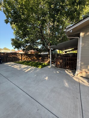 A backyard with a concrete patio, a wooden fence, and a covered area. - Perfect 2-bedroom apartment in welcoming Loveland for your stay (Loveland)