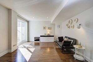 A modern living room with a sofa, a small table, and a cabinet. There is a window providing natural light and a view outside.