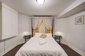 Ett hotellrum med en säng, två sängbord med lampor, en himmelssäng, en garderob och en inramad tavla på väggen.