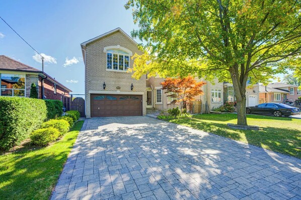 A residential house with a brick facade, a garage, and a paved driveway.