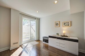 A room with a sliding glass door leading to a staircase, a white cabinet with drawers, and two framed pictures on the wall.
