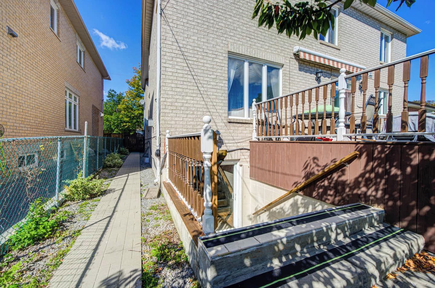 En bostadsbyggnad med en fasad av tegel, en trappa av trä och ett staket av metall.