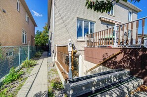 En bostadsbyggnad med en fasad av tegel, en trappa av trä och ett staket av metall.