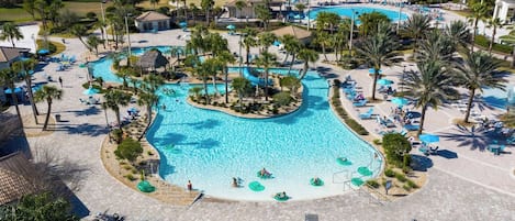 A resort with a large swimming pool, sun loungers, and a palm tree-lined area.
