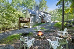 Een chalet met een terras, een vuurkuil en twee Adirondack-stoelen.