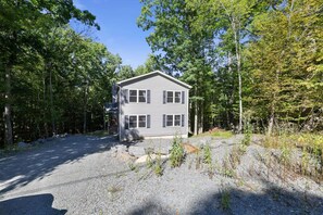 A two-story house with a gravel driveway and a forested backdrop. - Poconos Masthope 4BR Home Ski Big Bear - Lake Pool (Lackawaxen)
