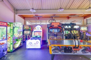 Een overdekte speelhal met diverse spelautomaten, waaronder een attractie gebaseerd op 'Jurassic Park' en een grijpmachine met 'Toy Zone'.