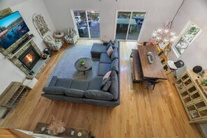 A spacious living room with a large sectional sofa, a fireplace, a dining area, and a view of the outdoors. - Poconos Masthope 4BR Home Ski Big Bear - Lake Pool (Lackawaxen)